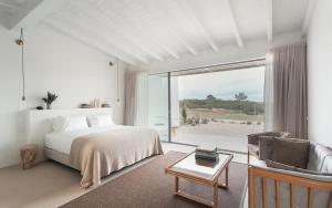 a white bedroom with a bed and a window at Amaria in Aljezur