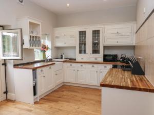 a kitchen with white cabinets and wooden floors at The Moorings in Wakefield