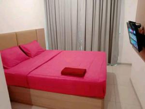 Un dormitorio con una cama rosa con aversión en Ryan dan Ilham Apartemen, en Dadap