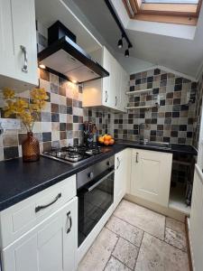 a kitchen with white cabinets and a black counter top at The Old Locksmith Cottage, Ulverston - Lake District in Ulverston