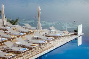 a group of chairs and umbrellas next to a swimming pool at Hotel Plaza in Pag