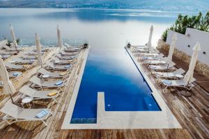 a row of chairs and a pool with water at Hotel Plaza in Pag