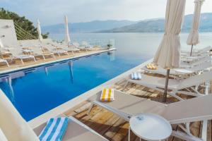 a pool with chairs and a view of the water at Hotel Plaza in Pag