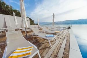 a row of white lounge chairs on a dock with the water at Hotel Plaza in Pag