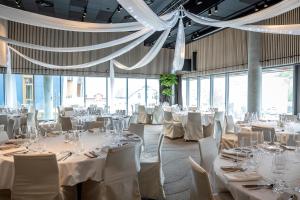 un salón de banquetes con mesas y sillas blancas y ventanas en Quality Hotel Richard With, en Stokmarknes