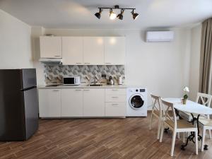 a kitchen with white cabinets and a table with chairs at Golden Sands Apartments Zlatna Kotva in Golden Sands