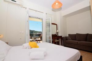 a bedroom with a white bed with a yellow hat on it at Villa Ektoras by EY Villas in Parga