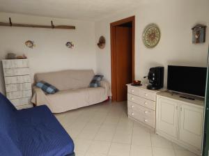 uma sala de estar com um sofá e uma televisão de ecrã plano em BILOCALE MAZZARELLI em Marina di Ragusa