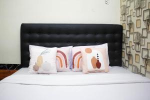 1 cama con 4 almohadas y cabecero negro en Capital O 2258 Santana Syariah Guest House en Solo