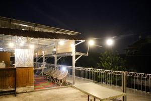 a deck with chairs and a table at night at Capital O 2258 Santana Syariah Guest House in Solo