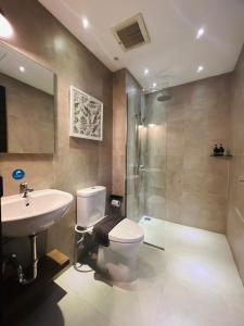 een badkamer met een toilet, een wastafel en een douche bij oxy suites 2-06 at Shop House Meisterstadt Pollux Habibie in Batam Center