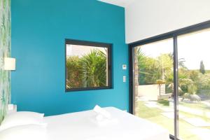 ein blaues Zimmer mit einem Bett und einem Fenster in der Unterkunft Stunning air-conditioned villa "Ronsard" with swimming pool in Saint-Aygulf
