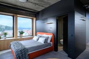 a bedroom with an orange bed in a room with windows at Delo 2.0. in Ljubljana