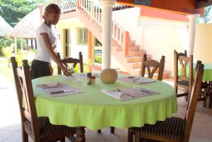 uma mulher de pé numa mesa com uma toalha de mesa verde em Hôtel Alizé Plage em Baguida