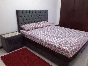 a bedroom with a bed with a black headboard and a red rug at Appartement in Agadir