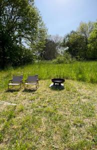 duas cadeiras e uma mesa de piquenique num campo em Mellem-rummet Guesthouse & Glamping em Tanderup