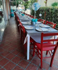 uma mesa longa com cadeiras vermelhas e decorações azuis em San Quirico Locanda ristorante pizzeria em Barbarasco
