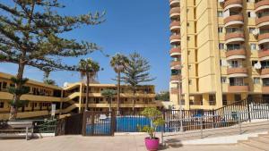 een geel appartementengebouw met een zwembad ervoor bij Torres Del Sol , Las Americas , cute apartment in Arona