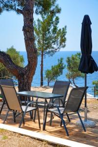 einen Tisch, Stühle und einen Regenschirm auf einer Terrasse in der Unterkunft Acroterra - Easy Living in Aliki
