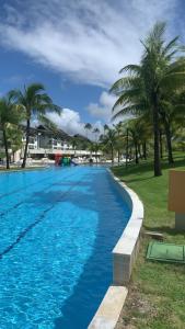 uma piscina com água azul e palmeiras em Beach Class Resort Muro Alto BMS em Porto de Galinhas