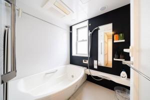 W łazience znajduje się biała wanna i umywalka. w obiekcie Generous Forest 301 w Tokio