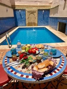 a table with plates of food next to a swimming pool at Riad Zahraa Al Ismailia in Meknès