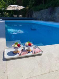 twee schalen aardbeien en lepels op een dienblad naast een zwembad bij Villa Lilia in Vietri