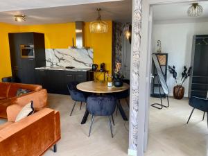 a kitchen and a living room with a table and chairs at Glücklich am Meer Suite Deluxe mit Wellnesszugang in Egmond aan Zee