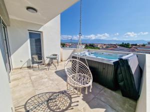a balcony with a swing and a swimming pool at 4 GENTLEMEN VILLAS with private jacuzzi in Novalja