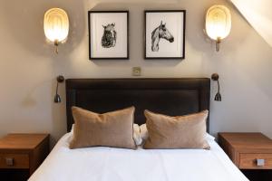 um quarto com uma cama com duas fotografias de cavalos na parede em Stirrups Hotel em Bracknell