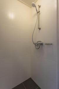 een douche in een badkamer met een witte muur bij Gasthuis Dokkum in Dokkum