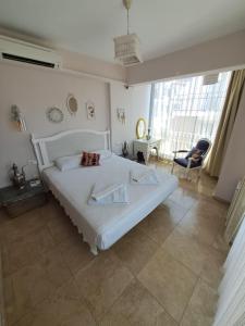 a bedroom with a large white bed and a chair at Smyrna Pansiyon in Kas