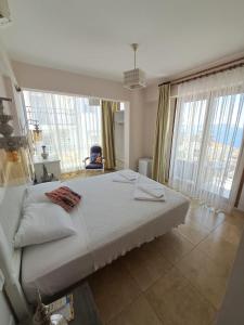 a bedroom with a large bed and large windows at Smyrna Pansiyon in Kas