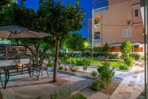 ロードス・タウンにあるMonte Smith Luxury Garden Apartment With Parkingの夜の庭園のテーブルと傘