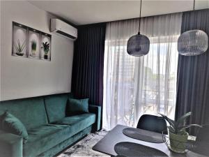 ヴィリニュスにあるAurea apartmentのリビングルーム(緑のソファ、テーブル付)