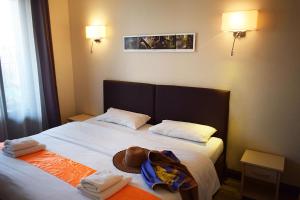a bed with two towels and a hat on it at Logis Hôtel Restaurant Le Top du Roulier in Capendu