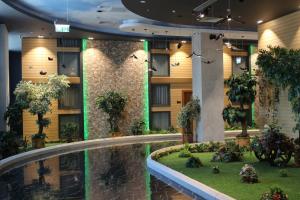 a hotel lobby with a swimming pool and plants at Midtown Hotel Baku in Baku
