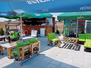 a store with green chairs and tables and an umbrella at къщички Поляните in Sinemorets