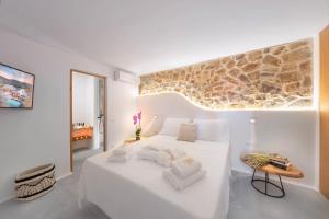 a white bedroom with a large bed and a table at Legendary Suites in Mýkonos City