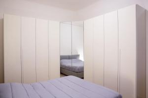a white bedroom with a bed and a mirror at Appartamento Adda10 in Milan