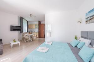 a living room with a large blue bed and a kitchen at Apartament z balkonem Lazur 250m od morza in Kołobrzeg