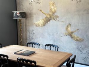 Central village house in Bussiere Poitevine في Bussière-Portevine: طاولة غرفة الطعام مع الطيور على الحائط
