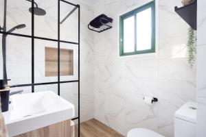 ein weißes Badezimmer mit Waschbecken und Fenster in der Unterkunft Acogedor Apartamento con vistas al mar en Costa Adeje in Adeje + 36 Fotos