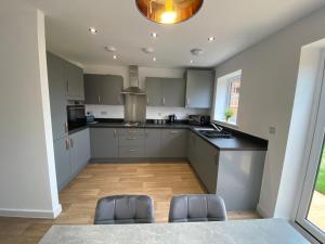 eine Küche mit grauen Schränken und zwei Stühlen darin in der Unterkunft Kingsway House - Spacious 4 Bed Home From Home in Derby in Derby