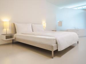 1 cama blanca grande en una habitación con 2 lámparas en Greulich Design & Boutique Hotel, en Zúrich