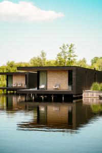 a house on a dock next to a body of water at Haven Lake Village in Kortenhoef