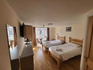 ein Hotelzimmer mit 2 Betten und einem TV in der Unterkunft The Grand Harbour hotel in Ilfracombe