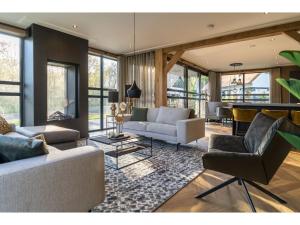 a living room with couches and tables and windows at Luxury villa with sauna only a few minutes from the beach in De Cocksdorp