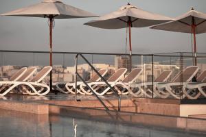 a group of white chairs and umbrellas on a roof at Grands Suites Hotel Residences and Spa in Il-Gżira