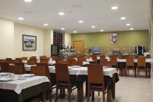 a dining room with tables and chairs and a kitchen at Hotel Dom Afonso - Monção in Monção